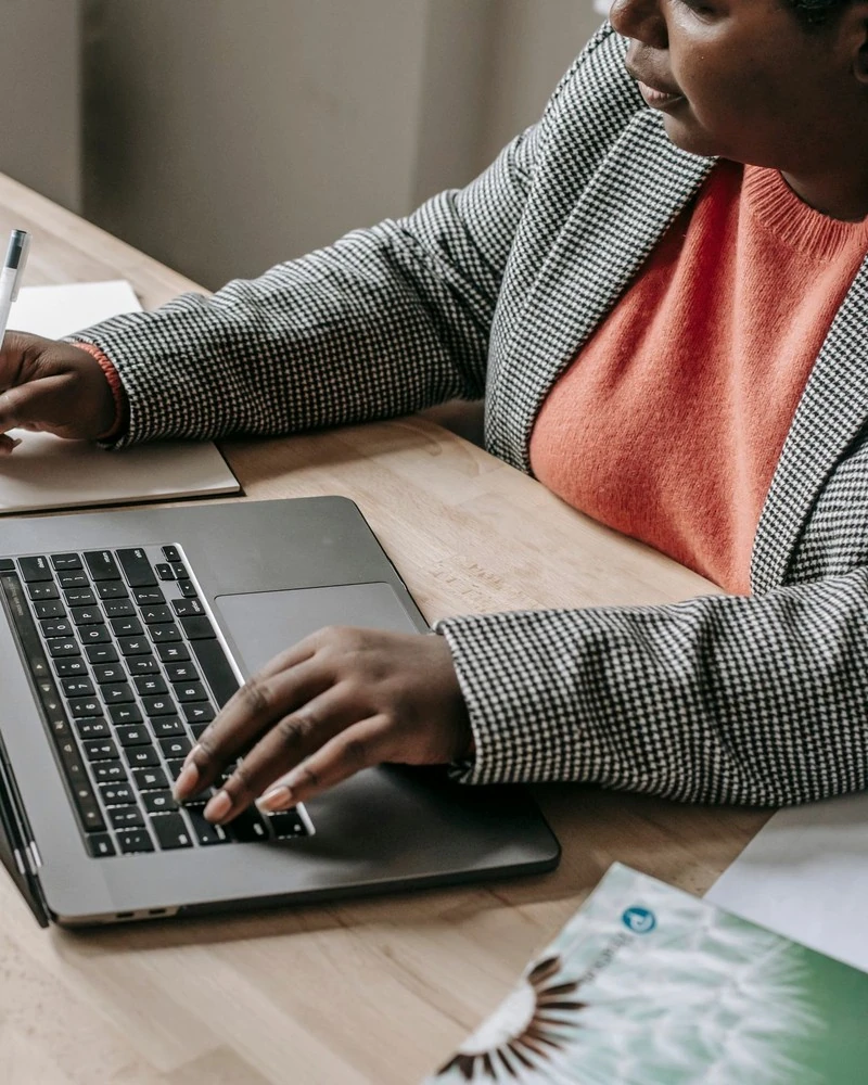 A woman answers her mail at a laptop and takes notes
