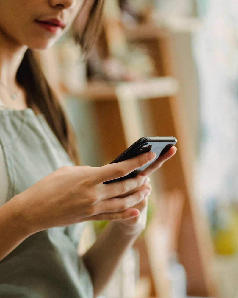 A florist reads her mail on her phone in her shop